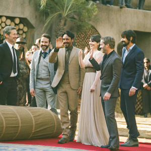 Ben Mendelsohn, Mads Mikkelsen, Riz Ahmed, Felicity Jones, Diego Luna, Alan Tudyk, and Donnie Yen gather at the Hollywood premiere of Star Wars: Rogue One. They are dressed in formal attire.