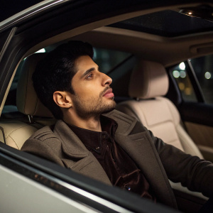 Close-up candid of Sidharth Malhotra in car. Luxurious interior, dark lighting. Contemplative look with short beard.