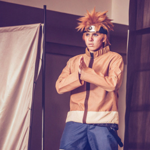Naruto Uzumaki from the anime series, determined look with sharp eyes. Orange hair, traditional outfit. Gray backdrop, event setting