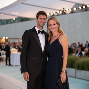 Formal attire, Novak Djokovic Foundation gala. Posing couple, blurred audience in background.