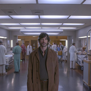 Eoin Macken as Dr. TC Callahan, standing in the bustling emergency room of a hospital. Bright lights, doctors and nurses in the background