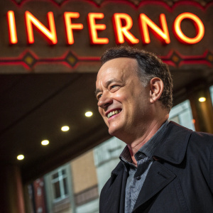 Promotional image for 'Inferno'. Tom Hanks, beaming, against vibrant 'INFERNO' backdrop. Filmed on Berlin set. Dynamic lighting