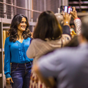 Salma Hayek at a casual meet and greet event. Wearing a blue blouse with jeans. No backdrop