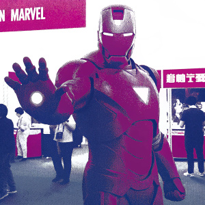 Robert Downey Jr., portraying Iron Man, standing in a dynamic pose. Background filled with text in English promoting a Marvel event. The metallic texture of his suit is highlighted, along with his intense expression. Scene set at a Marvel exhibition.