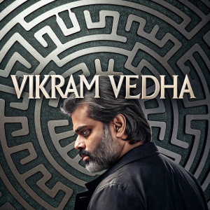 Promotional poster for 'Vikram Vedha', a Tamil movie. Vibrant and intricate design, with stylized silver text in Tamil script. The background features a maze-like pattern in shades of black and gray, creating a labyrinth effect.