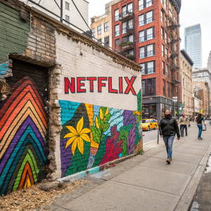 A vibrant street art mural featuring the Netflix logo. The colorful design covers a dilapidated brick wall in a bustling city.