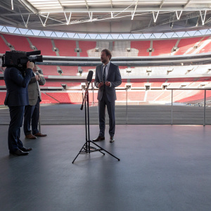 Gareth Southgate, in a formal suit, conducting a press conference at Wembley Stadium.