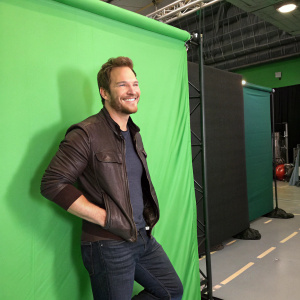 Chris Pratt, with a grin, at a sci-fi convention. Green screen backdrop