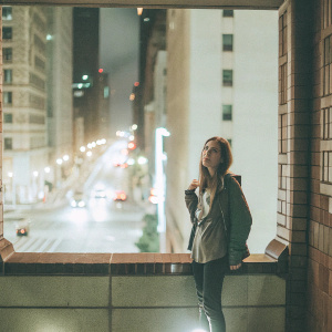 Aubrey Plaza, standing solo, against a bustling cityscape backdrop at night.