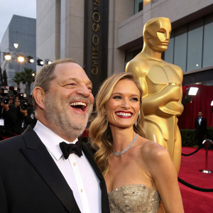Harvey Weinstein and Eve Chilton Weinstein grinning beside an Oscar statue at the Golden Globe Awards.