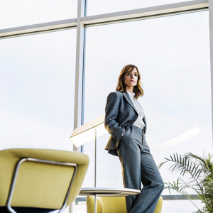 Emma Watson as Hermione Granger, in a sleek modern office setting. Wearing a business suit and a neutral expression.