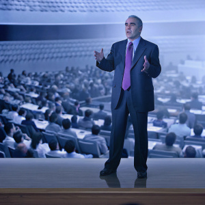 Garry Kasparov delivering a keynote speech. Wearing a dark suit and purple tie. The audience is captivated.