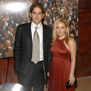 Michael Imperioli and Victoria Imperioli at the season premiere of 'The Sopranos'. Michael in a classic black suit, Victoria in a stunning red dress. A vibrant crowd and flashing cameras fill the background.