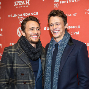 James Franco and Tommy O'Haver, smiling at the Sundance Film Festival. They are wearing matching suits and scarves.