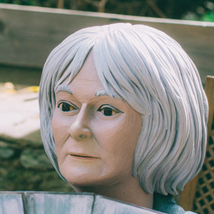 Tilda Swinton's close-up portrait. Detailed, lifelike. White hair contrasting against brown background.