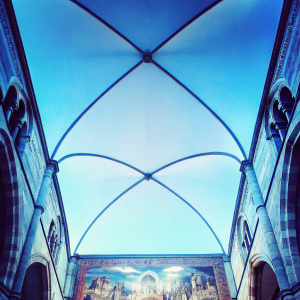 Stunning interior of Como Cathedral. Gothic architecture, detailed arches, and large tapestries depicting religious scenes.