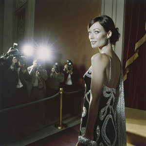 Olivia Wilde at the awards show, wearing an elegant black dress with silver embellishments. Surrounded by paparazzi and flashing lights.