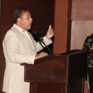 Gustavo Rangel, Venezuela's Defense Minister, passionately delivering a speech at a military event. Green backdrop