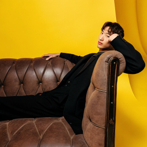 Kim Young-Kwang, South Korean actor, in a black suit, poses at a press conference for a KBS drama. The backdrop is white and he stands still with a posed expression.