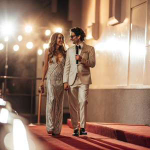 Jessica Alba and Neil Blumenthal attending the Webby Awards. Dark blue carpet. Bright stage lights