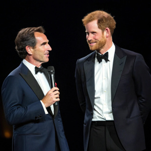Prince Harry and journalist Bob Woodruff at a charity event. Both in formal attire. Dark stage background