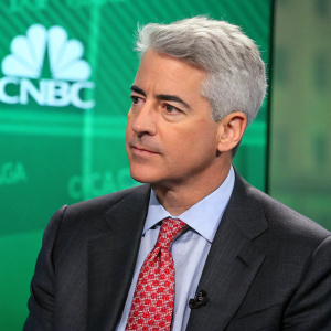 Bill Ackman on CNBC live, wearing a charcoal suit, light blue shirt, red pattern tie. Serious expression, against green screen