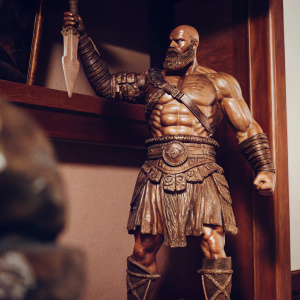 Detailed bronze statue of Kratos from God of War. Muscular, fierce expression. Dark, ominous background