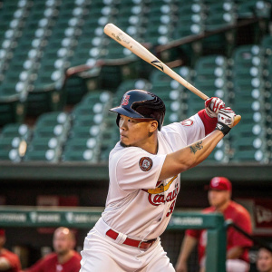 Kolten Wong, baseball player, dressed in a custom jersey. Focused on hitting the ball. Sparse stadium background.