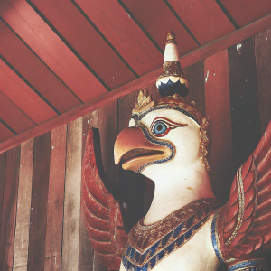 A stunning depiction of a mythical bird from Thai culture, the Garuda, showcased in vibrant colors. The creature's pristine white body is embellished with gleaming gold and striking blue accents. Its majestic headdress emits a radiant glow.