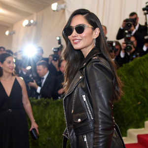 Olivia Munn at the fashion gala, wearing a black leather jacket and stylish sunglasses, amidst a crowd of photographers.