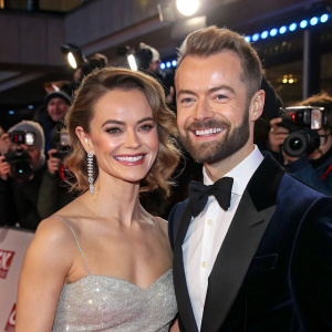 Kara Tointon and Artem Chigvintsev at a glamorous awards show. They are dressed in formal attire and smiling broadly. The background is filled with flashing cameras and excited fans.