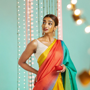 Radhika Apte, wearing a vibrant saree, at a film festival. Golden earrings and simple makeup. Festive decorations and lights in the background.