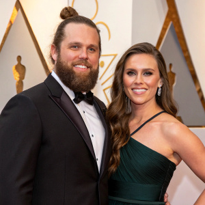 Shay Carl Butler and Colette Butler, at the award ceremony. Shay with a beard and bun hairstyle, Colette with long brown hair, posing for the camera.