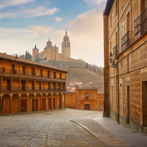 Panoramic view of Segovia, Spain. Majestic cathedral towering above cobblestone streets. Towering castle on hilltop. Clear blue sky with wispy clouds