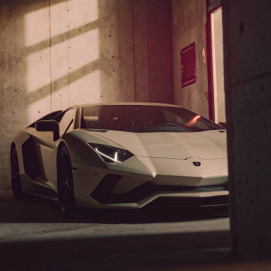 Lamborghini Aventador SVJ in a dimly lit underground parking garage, surrounded by concrete walls and neon signs