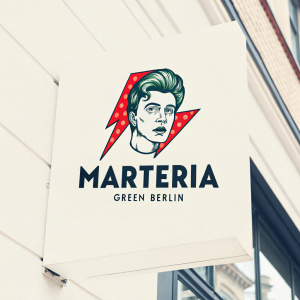 Marteria Green Berlin logo design featuring a stylized face and bold red lightning bolt. The brand name 'Marteria Green Berlin' is displayed in a simple font below. Bright red against light background. Contemporary graphic design with strong brand emphasis.