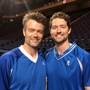 Josh Duhamel and Matthew Morrison standing together, friendly pose. Blue sports jerseys. Behind them, empty auditorium.