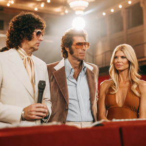 Howard Stern and Beth Ostrosky Stern at an awards show. Bradley Cooper in a blue shirt and gray jacket, standing alongside them.