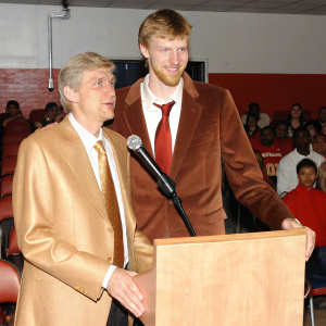 Arsene Wenger and Per Mertesacker during a Q&A session. A bustling audience in the background.