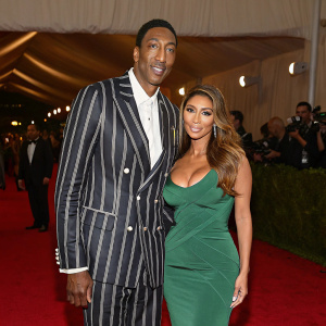 Scottie Pippen and Larsa Pippen at a gala event. Scottie in a stylish striped suit with white shirt, Larsa in a green dress. Red carpet ambiance