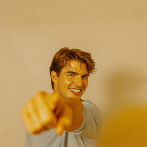 High-resolution close-up of Tom Cruise. Youthful look, short hair, warm smile. Wearing light blue t-shirt. Background blurred, focus on upper body and confident pose.