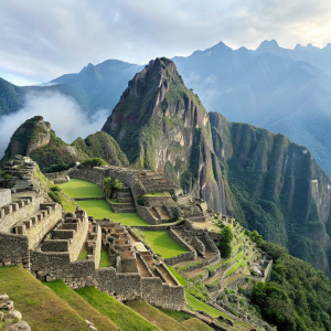 Ancient Inca ruins of Machu Picchu. Lush green vegetation. Stone structures layered on mountain ridge. Huayna Picchu towering behind