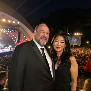 James Gandolfini and Deborah Lin at the Hollywood Bowl concert. Both are dressed in formal attire. Crowded venue, illuminated by stage lights.