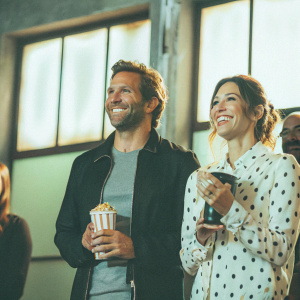 Bradley Cooper and Jessica Biel, Caucasian celebrities, smiling at MTV Movie Awards. He is in a black jacket, gray t-shirt. She wears a white polka dot blouse.