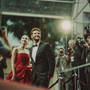 Jennifer Lawrence and Liam Hemsworth at an award ceremony. Red carpet event with flashing cameras and paparazzi