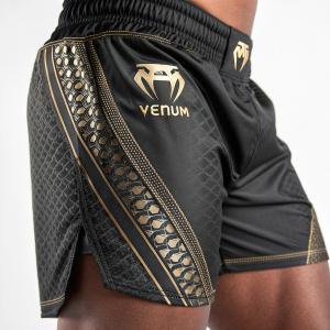 Close-up shot of Venum Muay Thai shorts. Black fabric with shiny Venum logo. Textured mesh pattern, repeated along side seam.