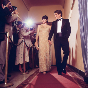 Shannen Doherty and Luke Perry at the 18th Annual People's Choice Awards. Doherty in a gold, beaded gown, Perry in a black tuxedo. They stand gracefully on the red carpet, surrounded by fans and photographers.