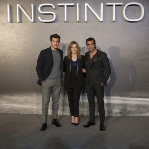 At the 'INSTINTO' film premiere, Mario Casas in a sharp black suit, Lola Duenas in a striking black blazer, and Oscar Casas in a sleek black ensemble. The backdrop showcases 'INSTINTO' in bold letters.