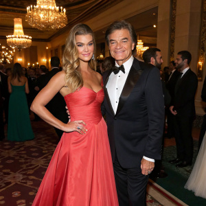 Nina Agdal and Dr. Mehmet Oz attending a glamorous charity gala. They are dressed in elegant evening wear.
