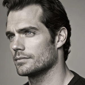 Close-up of Henry Cavill's face, intense gaze, detailed view of his facial features and hair. Grey scale photo
